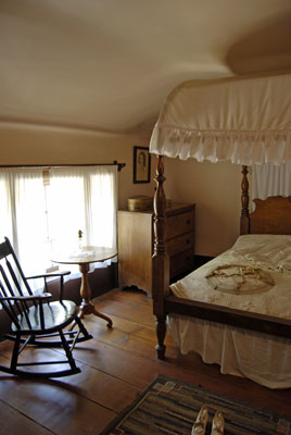 a quaint bedroom with four-poster bed and rocking chair