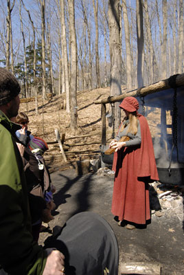 a woman in pioneer clothing demonstrates how maple syrup was made in pioneer days