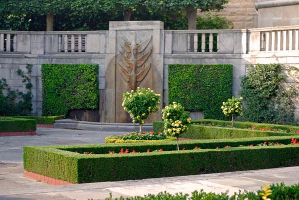 formal garden area with bas-relief wall ornamentation and flower beds bordered with clipped hedges